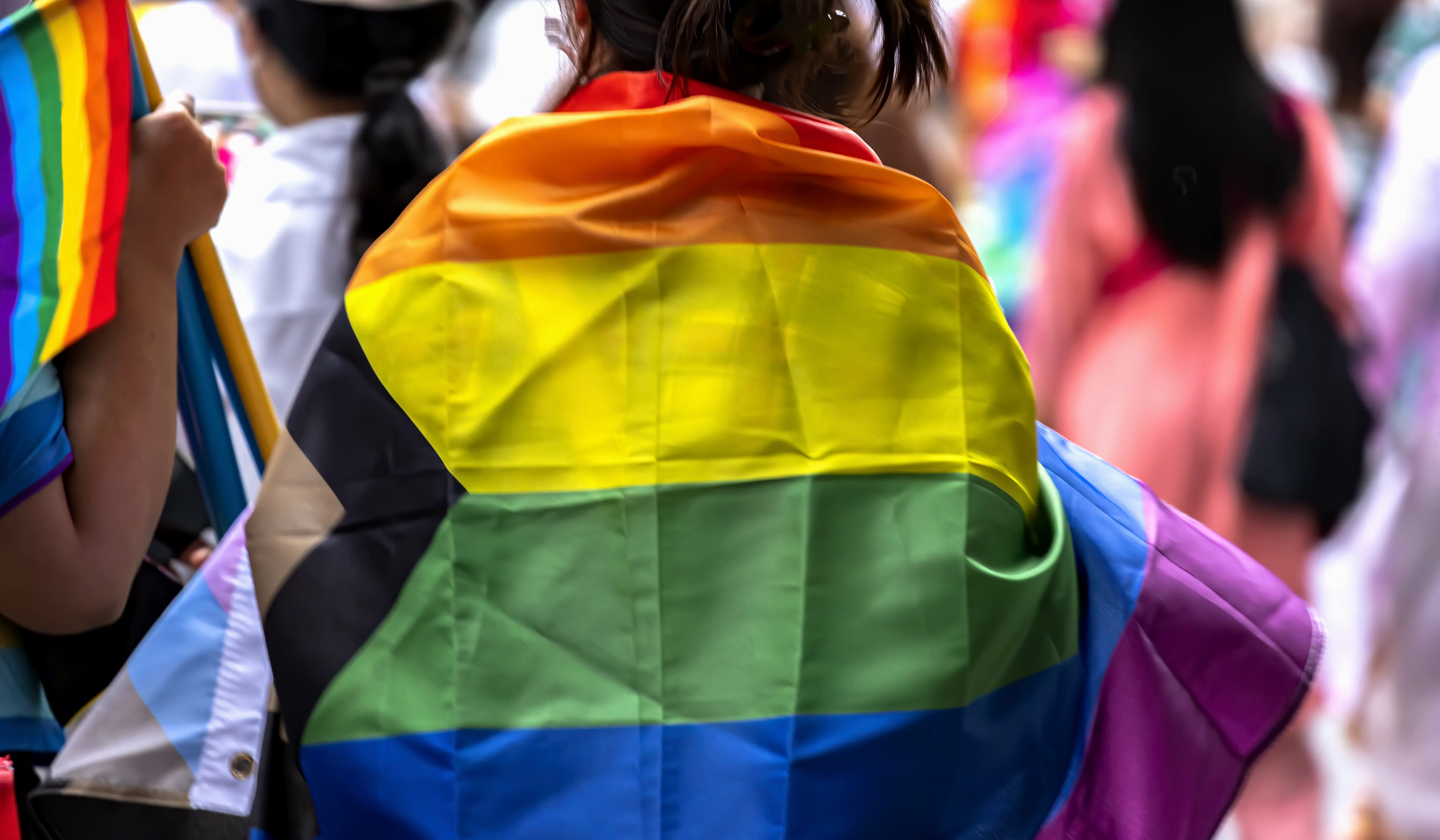 People marching with rainbow LGBT+ flag at a pride event
