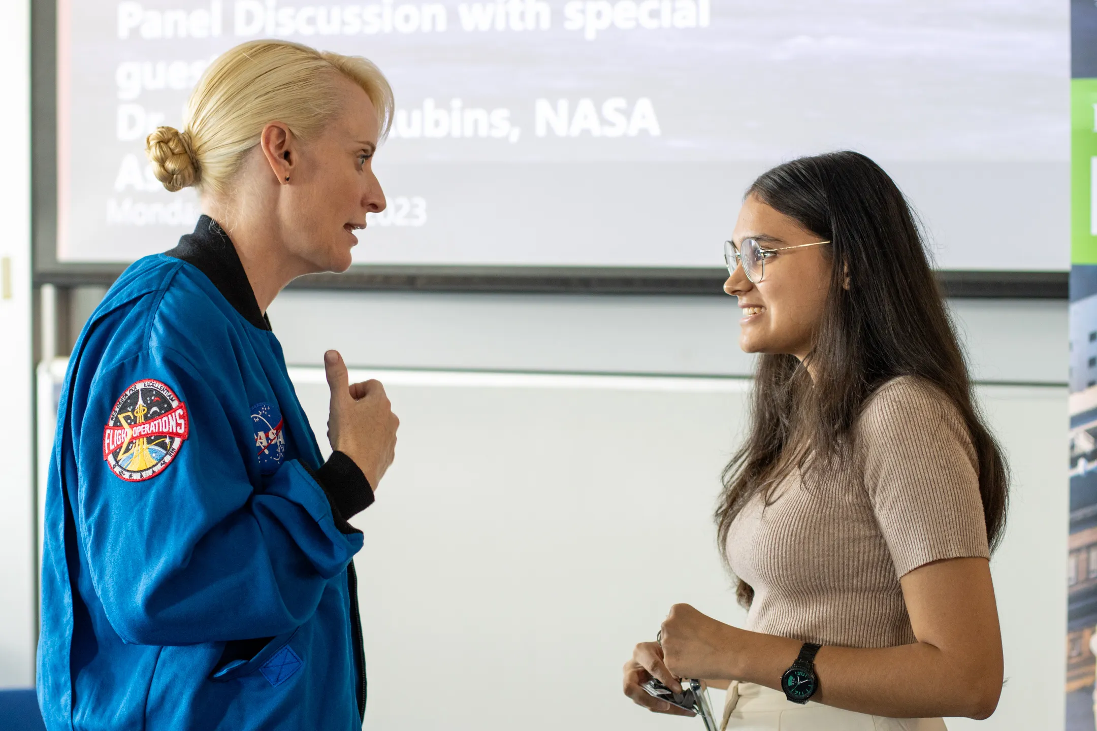 Kate Rubins is talking to a young woman after the panel discussion