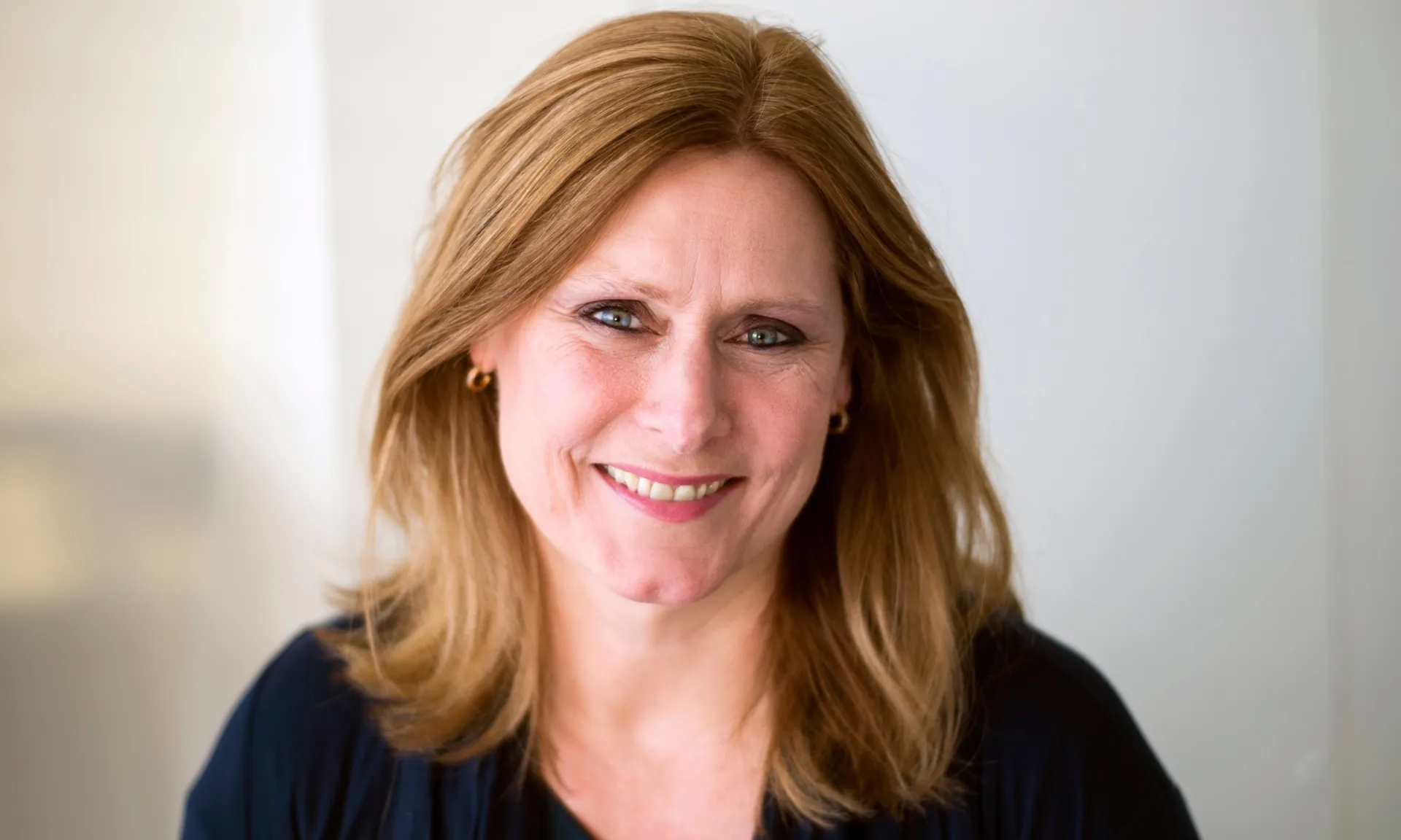 Sarah Brown smiling to camera in front of a neutral blurred background. 