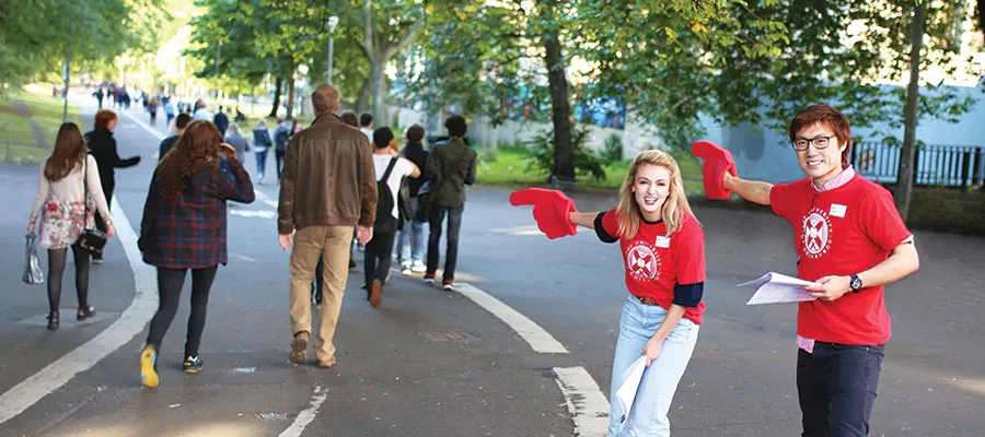 Students pointing along Middle Meadow Walk with large foam hands