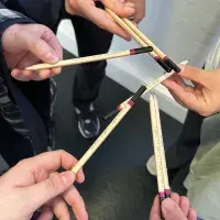 Hands hold pencils with 'Including All' engraved on them