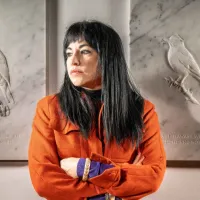 Artist Jasmina Cibic pictured standing in front of releifs carved from white marble, which form part of her piece 'Dawn Chorus' 