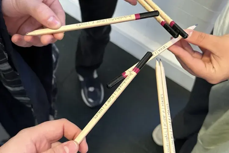Hands hold pencils with 'Including All' engraved on them