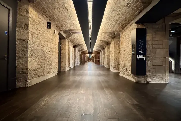 A long stone corridor with dark wooden flooring