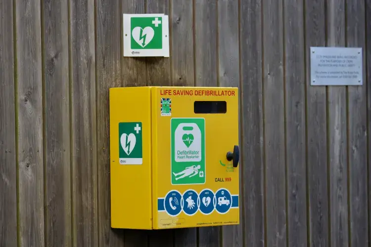 Defibrillator attached to the wooden wall in a park.