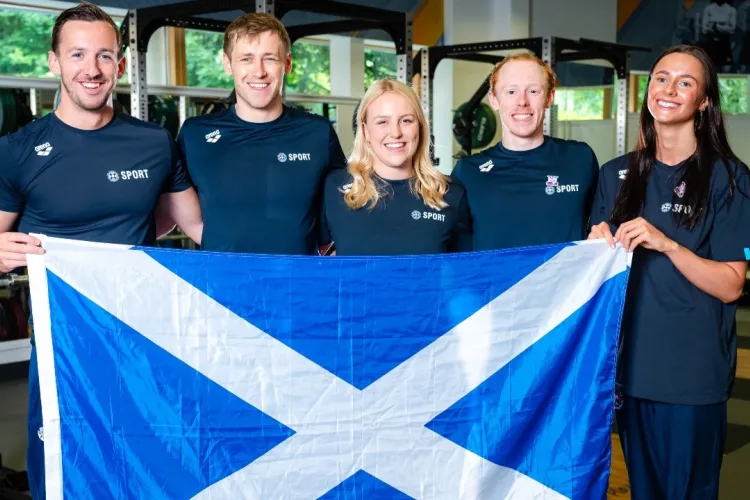 A group of swimmers from the University stand in a group holding a Scottish flag