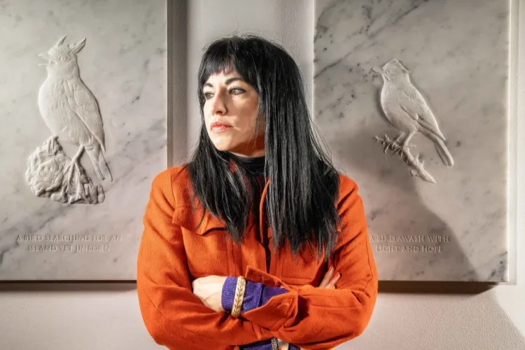 Artist Jasmina Cibic pictured standing in front of releifs carved from white marble, which form part of her piece 'Dawn Chorus' 