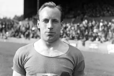 Athlete Eric Liddell stands on a sports field