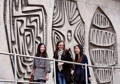 Photograph of our postgraduate students with backdrop of the amazing wall sculptures on our Charteris building 