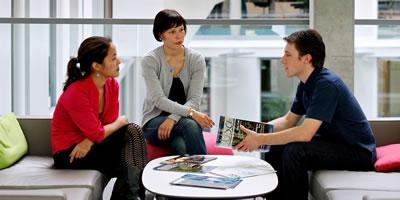 People discussing work at a seating area within the Informatics Forum atrium.