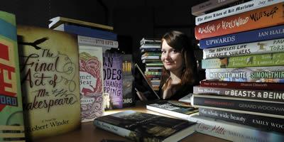 A student from the reading panel, surrounded by books submitted for the prize