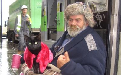 A homeless man sits with his cat