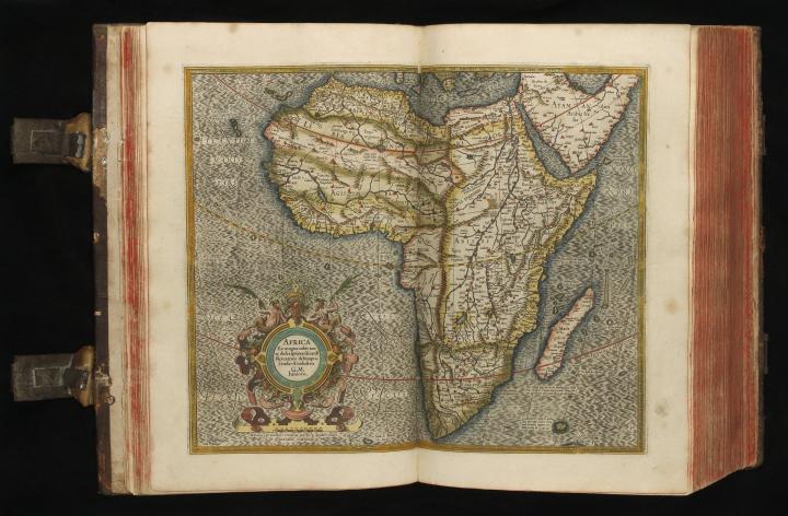 Large book open to show a map of Africa. The book has metal clasps which are visible.