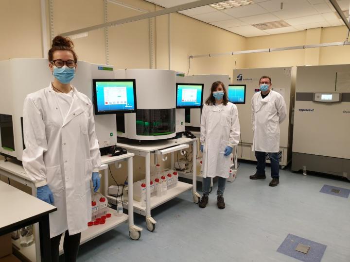 3 lab specialists standing next to DNA extraction Machine in the Western general Hospital Clinical Research Facility, Edinburgh
