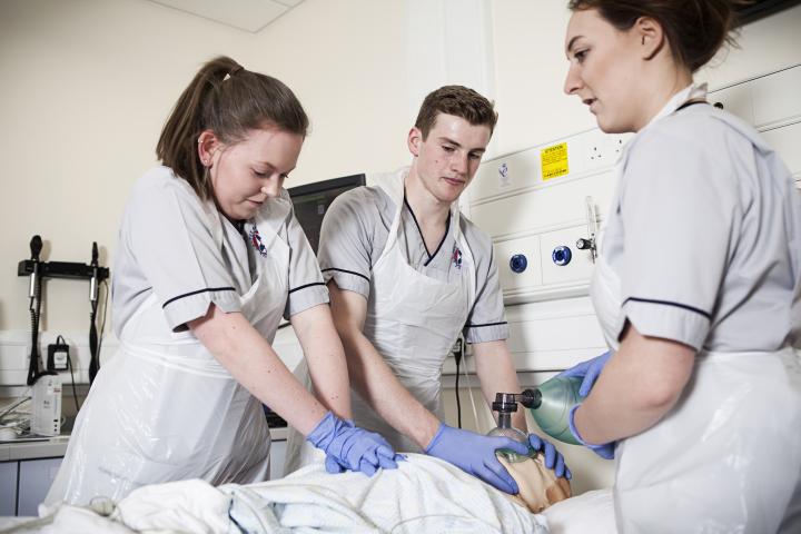 Three student nurses practice CPR on a dummy in one of their clinical elective sessions