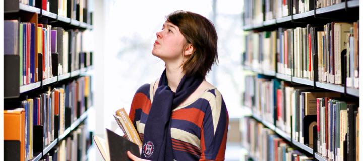 A woman looking up at a bookshelf