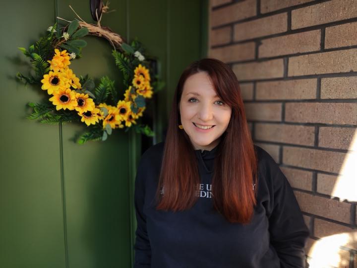 Image of volunteer in front of sunflower wreath 