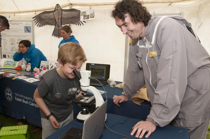 Roslin researcher shows a child how to use a microscope