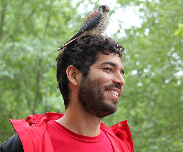 Photo of Andres Goens taken outside with a bird on his head
