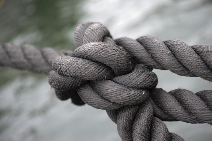 A photograph of a big tight knot within lengths of rope. 