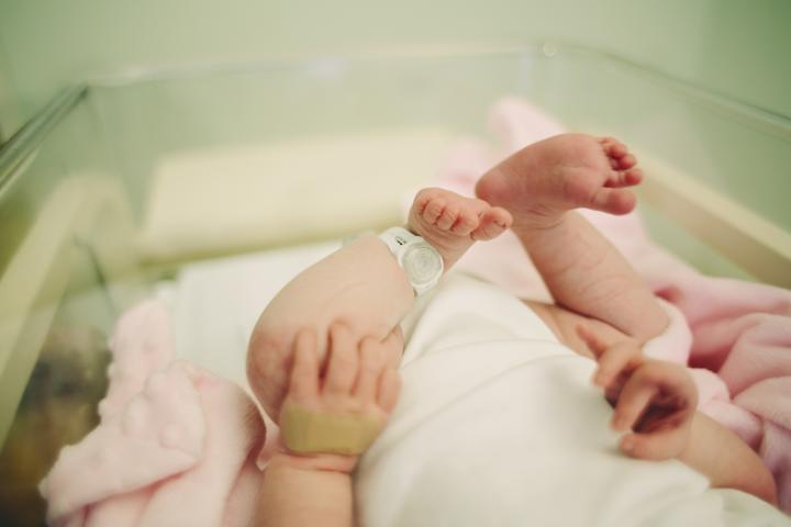 A photograph of a newborn baby's feet in a cot at the hosptial