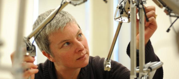 A photo of a woman with short, grey hair working with a roboticconstruction