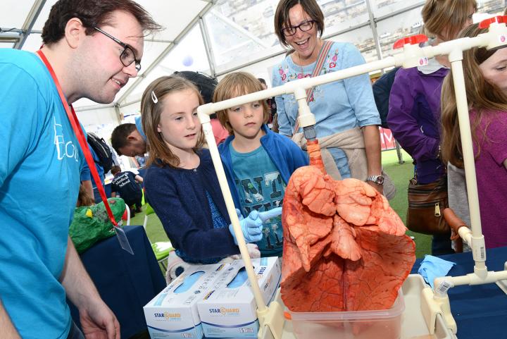 Adult and two children with a Roslin Institute researcher inflating a preserved pig lung to investigage its structure.