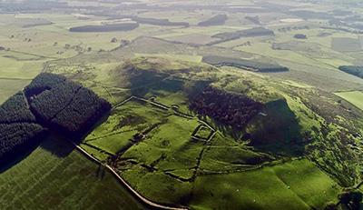Burnswark hillfort, SW Scotland, lines of an ancient hillfort are visible against a green hillside