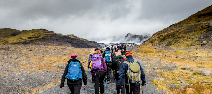 A group of university students in weather gear walking up a rocky slope towards a glacier in Iceland