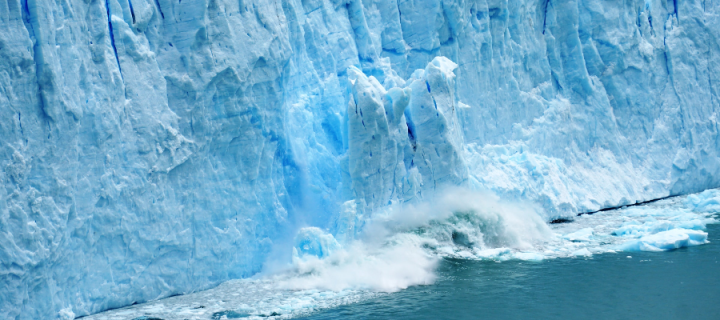 A large chunk of ice breaking off a glacier and splashing into the ocean