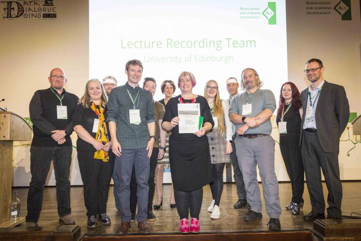 Picture of the team on stage holding the award and certificate