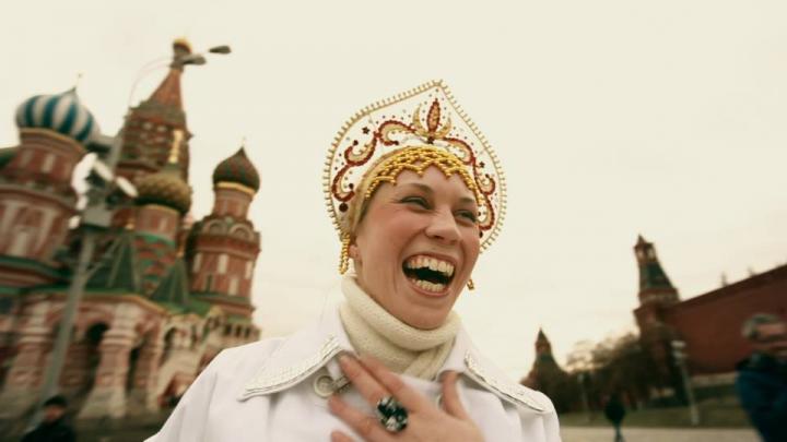 a woman in traditional Russian religious dress stands on Red Square laughing 