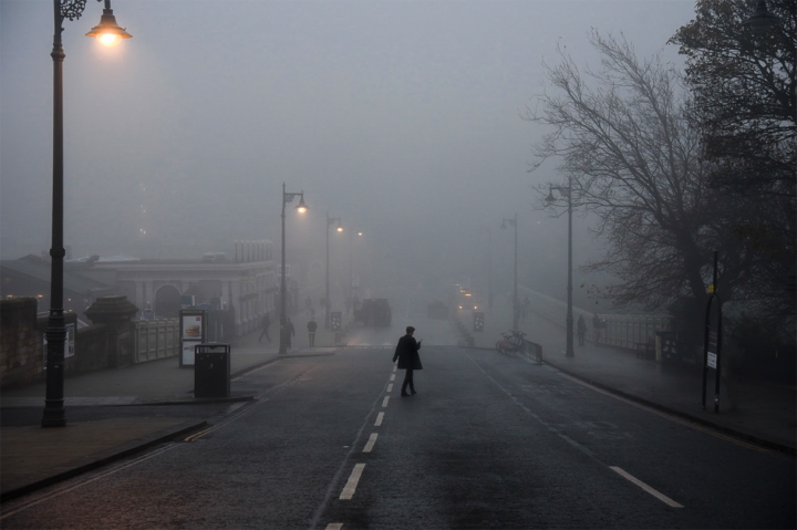 Waverley Bridge, Edinburgh, in the fog with a solitary figure crossing the street.