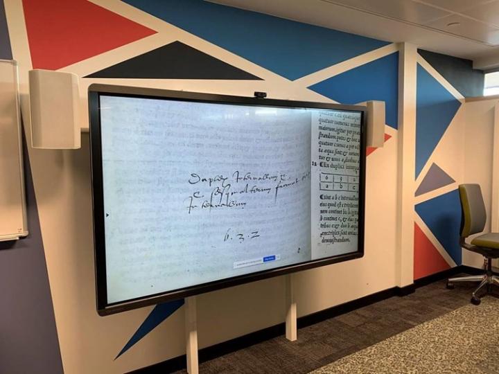 A photo of one of the digital smartboards in the Centre for Research Collections Reading Room. The smartboard is displaying a white piece of paper with hand written writing on it.