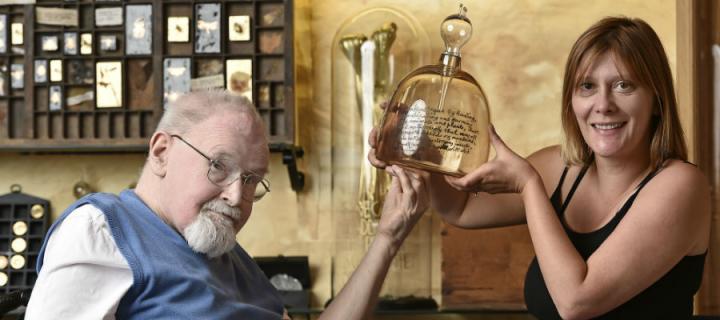 Photo of Alasdair Gray and Siobhan Healy holding an intricate glass artwork