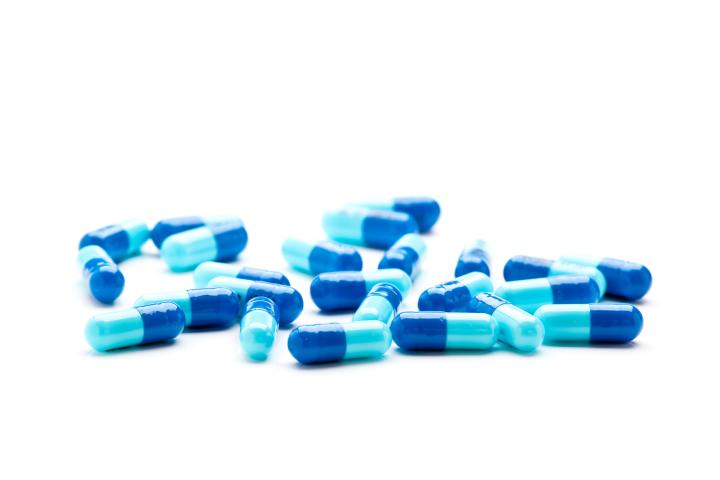 A photo of blue pills spread out on a white surface