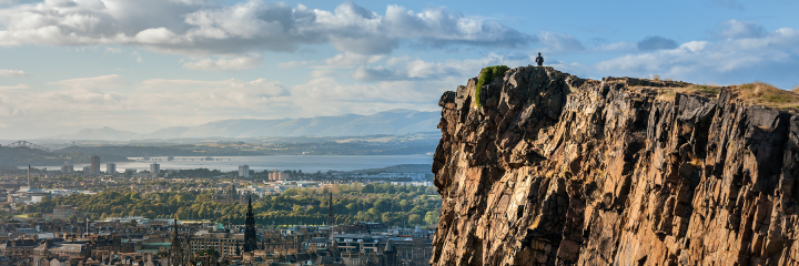 Edinburgh skyline with a man on top of craggy hill
