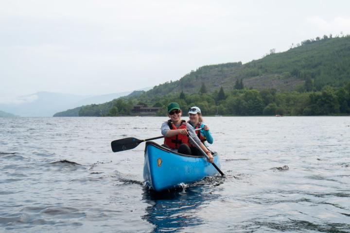 A young woman kayaks on a large lake.