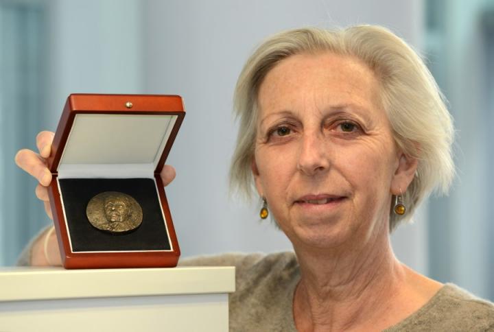 Professor Eleanor Riley holding the Ronald Ross Medal.