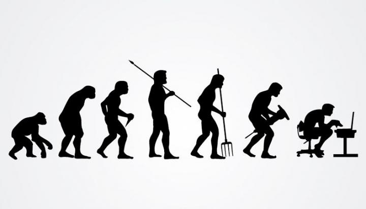 Black and white drawing of the evolution of man. The first silhouette is an ape. The next silhouettes show humans evolving to use tools. The final silhouette is a person sitting at a desk working on a computer. 