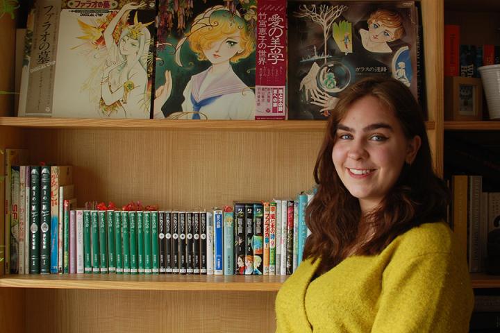 Photo of Francesca standing in front of a bookcase with her collection