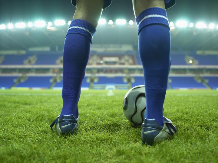 Legs of a footballer standing in a lit football stadium