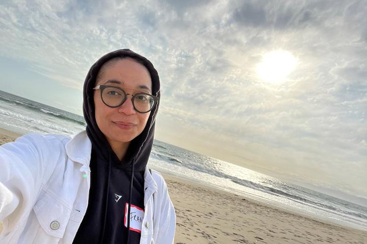 Head and shoulders photo of Francisca Da Silveira on a beach with her hood up