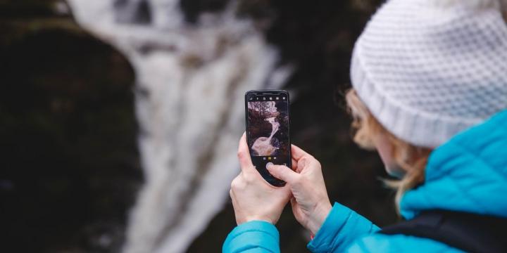Image of a waterfall and someone taking a picture of it on their phone