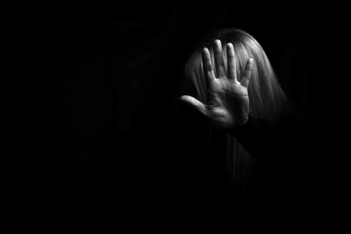 Black and white picture of woman in shadows holding hand up in stop motion 