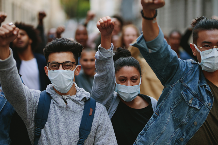 Group of young people protesting while wearing protective masks. 