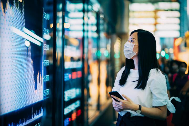 Woman with mask looks at financial data