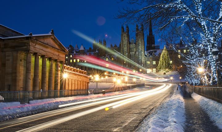 Light trails from traffic moving down The Mound in central Edinburgh, Scotland during December