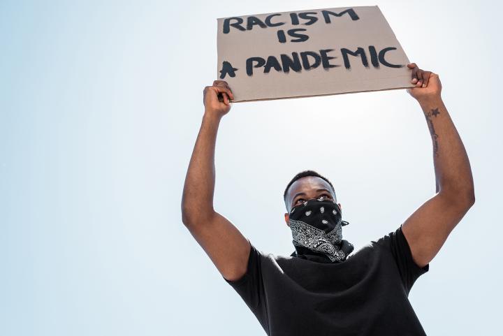 Protester holding a placard that states racism is a pandemic