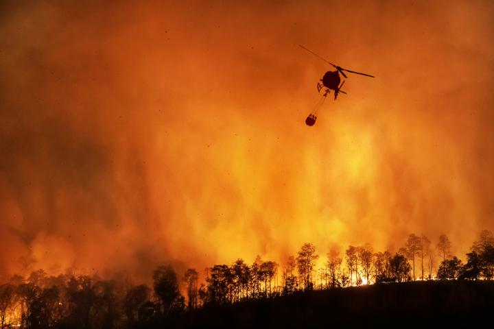 A helicopter tackles a forest fire in Thailand